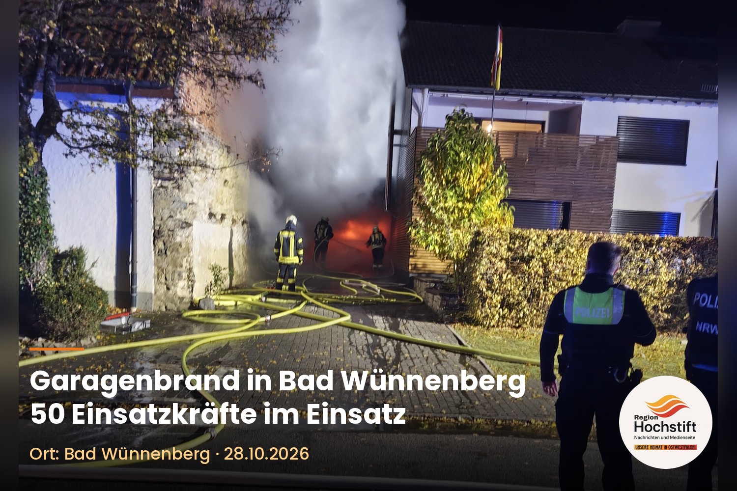 Feuerwehrleute löschen einen Garagenbrand in der Rosenstraße in Bad Wünnenberg, im Vordergrund Polizeikräfte