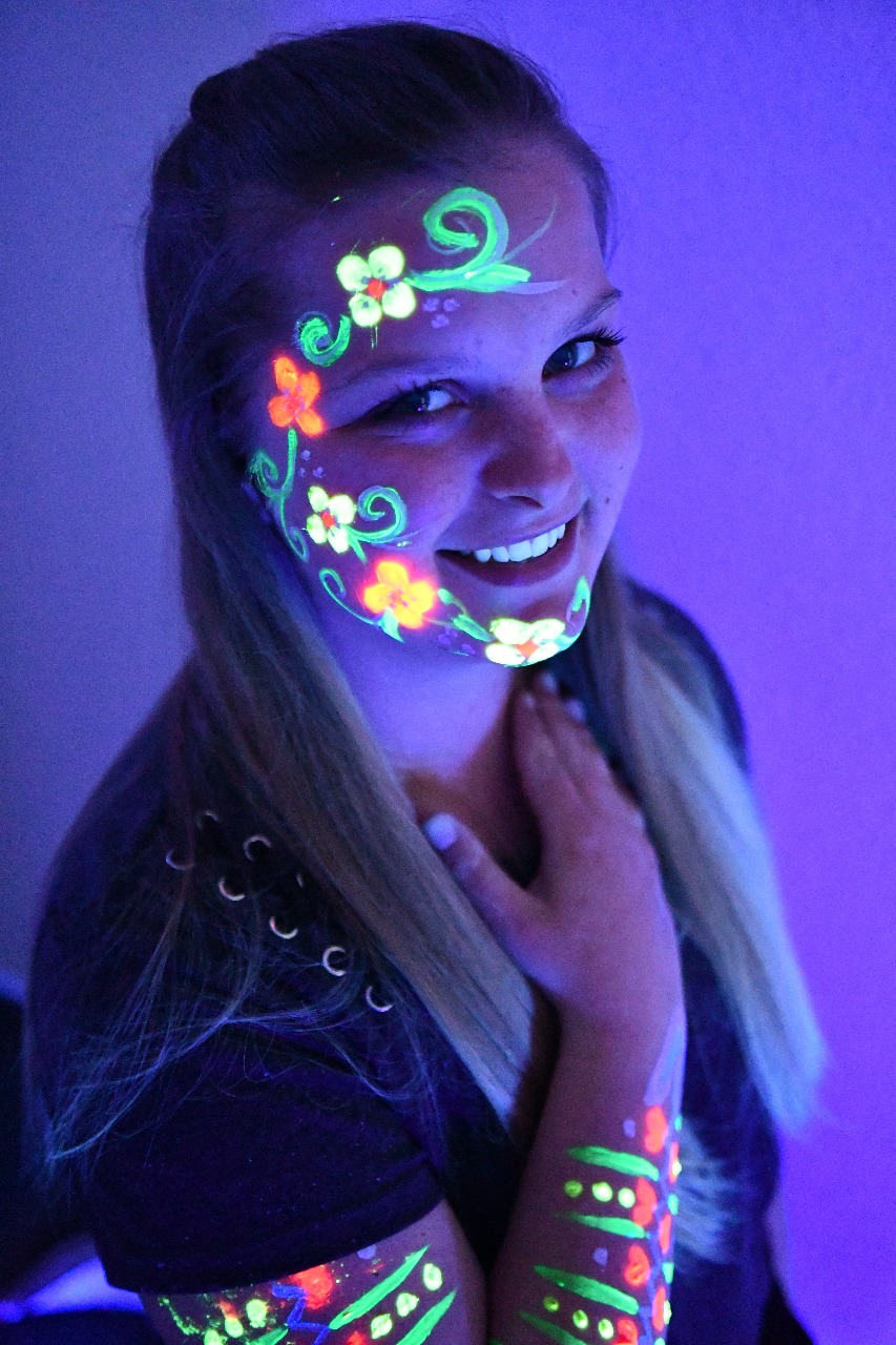Junge Frau mit leuchtendem Neon-Make-up im Schwarzlicht