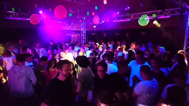 Tanzende Menschen unter bunten Lichteffekten in einer Halle