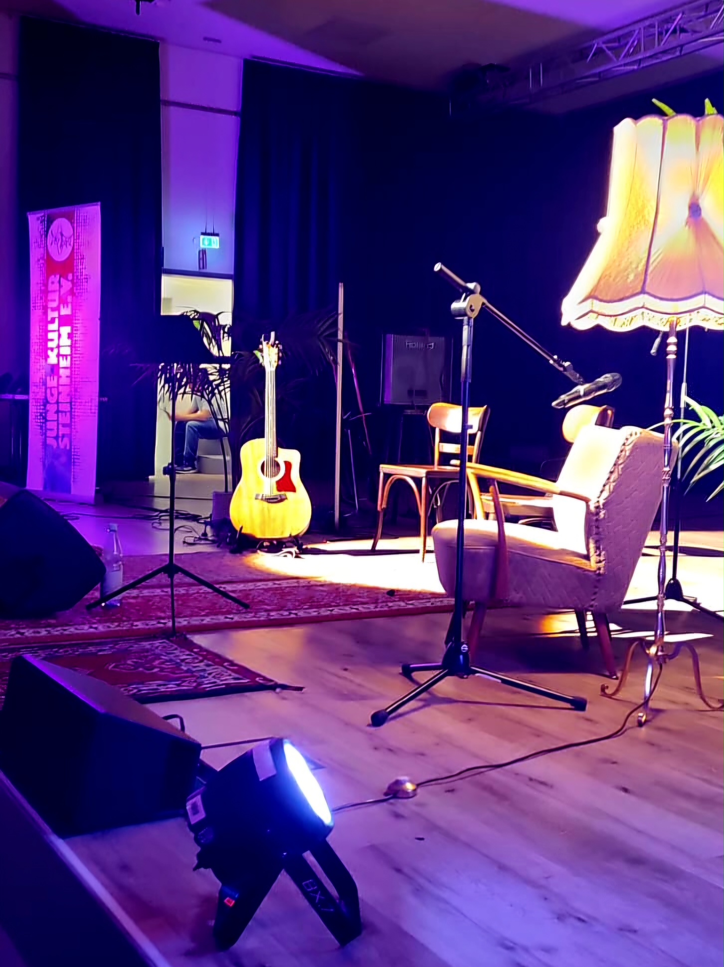 Bühne mit Gitarre, Sesseln und Stehlampe im Wohnzimmer-Ambiente