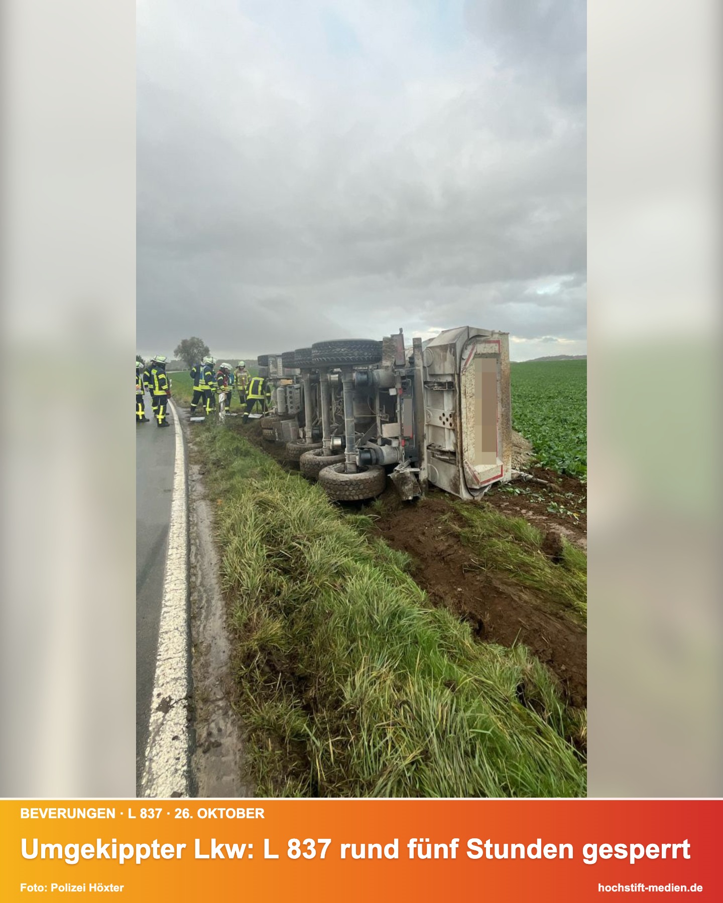 Umgekippter Lkw mit Auflieger neben der L 837 auf einem Feld, Einsatzkräfte im Hintergrund