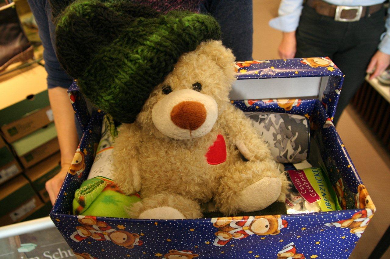 Mit Teddy, Mütze und Schulbedarf gefüllter Schuhkarton